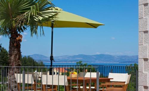a table and chairs with an umbrella on a balcony at Villa Angelina in Mirce