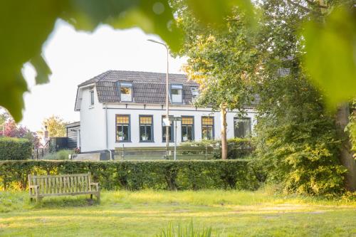 a bench in front of a white house at B&B Ons Dijkhuisje in Schuddebeurs