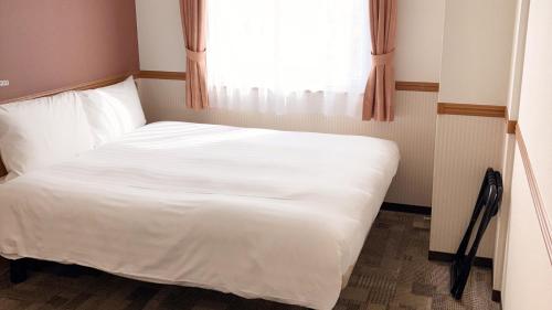 a white bed in a room with a window at Toyoko Inn Kofu eki Minami guchi No 1 in Kofu