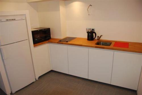 a kitchen with white cabinets and a counter top at Aparthotel Malpertuus in Aalst