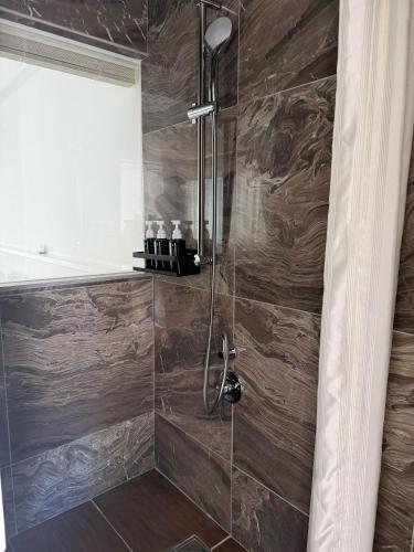 a bathroom with a walk in shower with wooden walls at WITH SEA Nakama in Onna