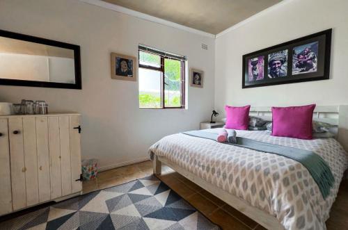 a bedroom with a large bed with pink pillows at Hermanus Backpackers & Budget Accommodation in Hermanus