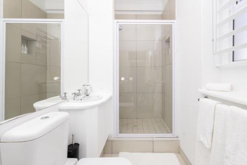a white bathroom with a shower and a sink at Villa Mykonos in Cape Town