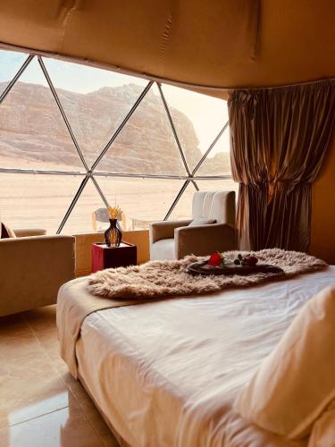 a large bed in a room with a large window at Wadi Rum Main Road Visitor Center in Disah