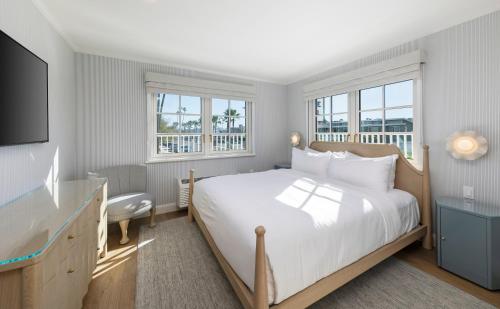 a bedroom with a large bed and a television at Bay Shores Peninsula Hotel in Newport Beach