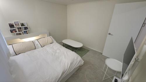 a white bedroom with a bed and a television at 모던한 스테이 in Samgong