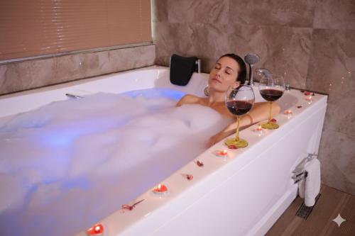a woman in a bath tub with two glasses of wine at Zengin City Hotel in Istanbul