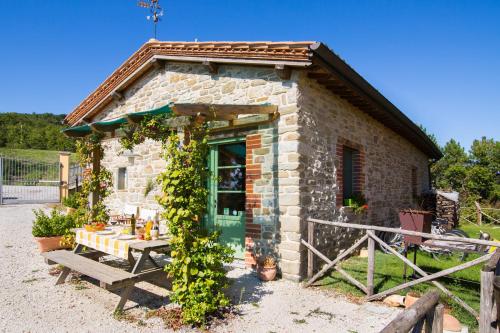 a small stone house with a table and a bench at Agriturismo La Coccinella in Valfabbrica