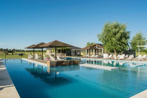 a large swimming pool with chairs and a house at Pampas del Sur - Hotel de Campo - Cañuelas in Cañuelas