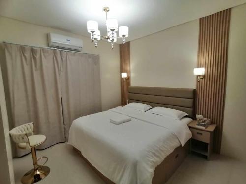 a bedroom with a large white bed and a chandelier at Casathea Hometel Cebu in Talisay