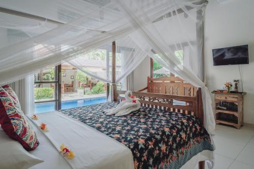 a bedroom with a bed with a canopy at Frangipani Beach Hotel in Lovina