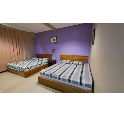 two beds in a room with purple walls at Hotel O Pavilion Inn Hotel in Lumut