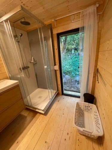 a bathroom with a shower and a window in a wooden house at Les Ecolodges du Lac in Chambon-sur-Lac