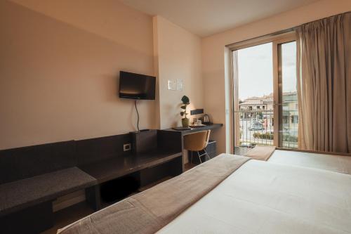 a hotel room with a bed and a desk and a window at Mod 05 Bike Hotel in Castelnuovo del Garda