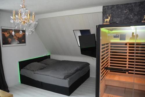 a small bedroom with a bed and a chandelier at Appartement am Diemelsee Infrarotsauna inklusive in Marsberg
