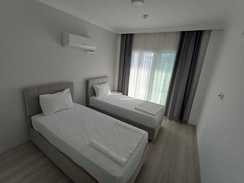 ein Hotelzimmer mit zwei Betten und einem Fenster in der Unterkunft Aykaç Hotel in Silifke