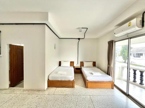 two beds in a room with a window at Bangsaphan Resort in Bang Saphan