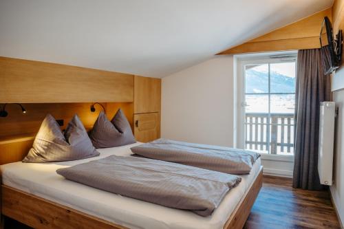 a bedroom with two beds and a large window at B&B Gästehaus Alpenblick in Lermoos