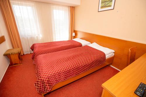 a hotel room with two beds with red checked sheets at Hotel Dominika in Bratislava