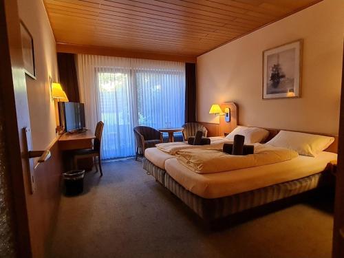 a hotel room with two beds and a desk and a television at Hotel-Barbarossa-Garni bei Hanau in Rodenbach
