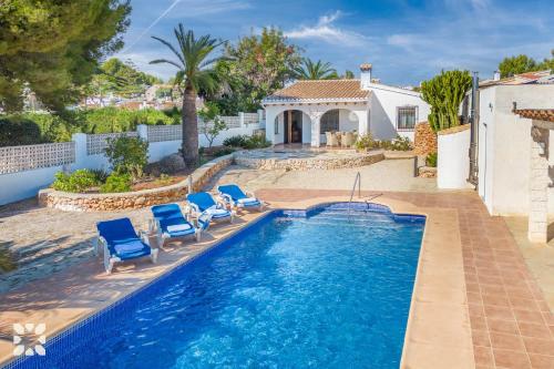 a swimming pool with chairs and a house at Villa Ananas by Abahana Villas in Moraira