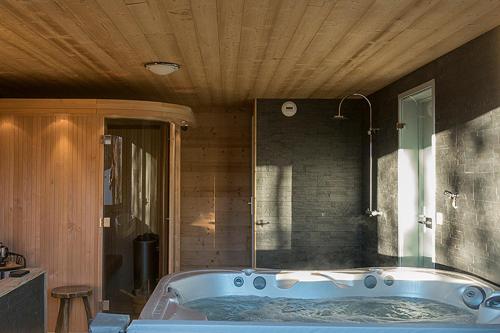 Chalet Yarelle في آلوفارْ: حوض استحمام في غرفة ذات سقف خشبي