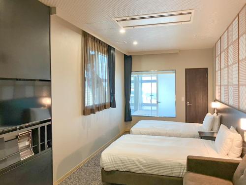 a hotel room with two beds and a flat screen tv at LiVEMAX Sakishima Cosmo Tower Hotel in Osaka