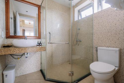 a bathroom with a shower and a toilet and a sink at The Shine Hotel & Apartment in Danang