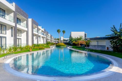 a swimming pool in front of a building at Palmera - Spacious Studio with Pool View in Vasilia