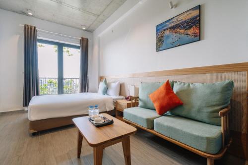 a hotel room with a bed and a couch and a table at The Shine Hotel & Apartment in Danang