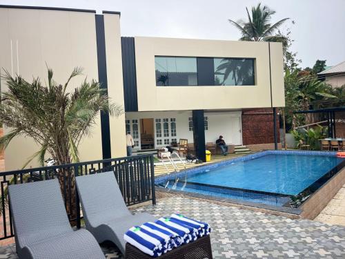 a swimming pool with two chairs and a house at Bumblebee Pool Villa Munnar in Anachal