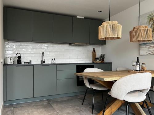 a kitchen with green cabinets and a wooden table at Olive Beach, luxury beachhouse 150 m from the beach in Noordwijk aan Zee