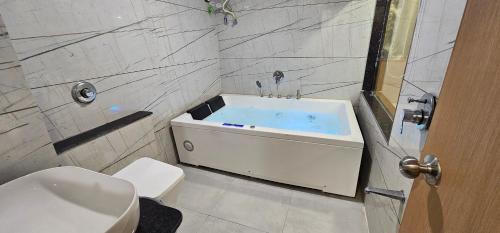 a bathroom with a tub with a toilet and a sink at Hotel Earth Orbit in Gandhinagar