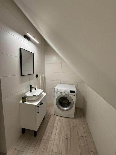 a bathroom with a washing machine and a sink at Domek Ostoja Energylandia Zator Graboszyce in Graboszyce