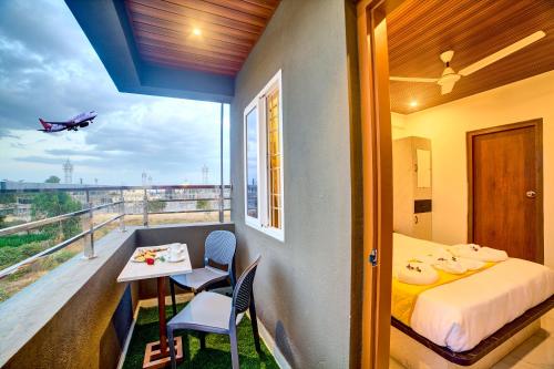 a bedroom with a balcony with a bed and a table at Hotel Airline Inn - Near Kempegowda International Airport in Muthugadahalli
