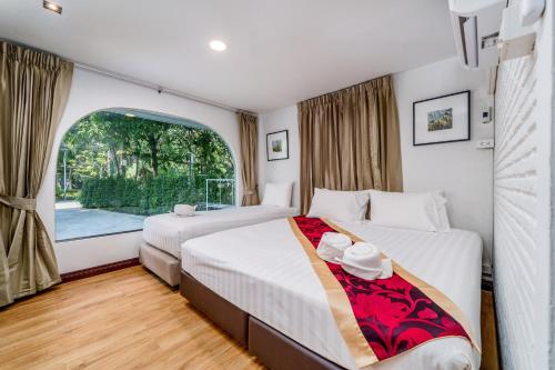 a bedroom with two beds and a large window at Villa Navin Premiere Pool Villa in Jomtien Beach