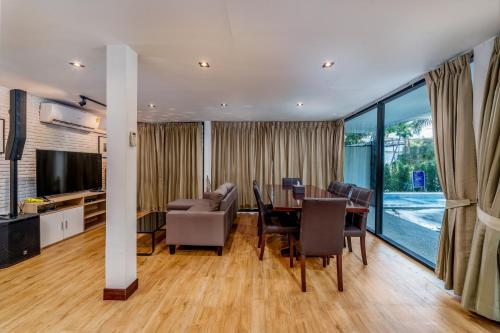 a dining room with a table and chairs and a television at Villa Navin Premiere Pool Villa in Jomtien Beach