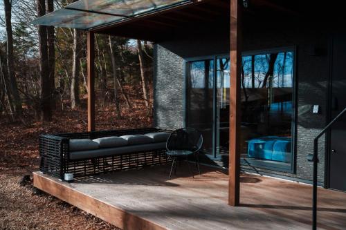 a house with a black couch on a deck at ツキミチル　〜軽井沢のサウナ・BBQつき一棟貸しホテル〜 in Miyota