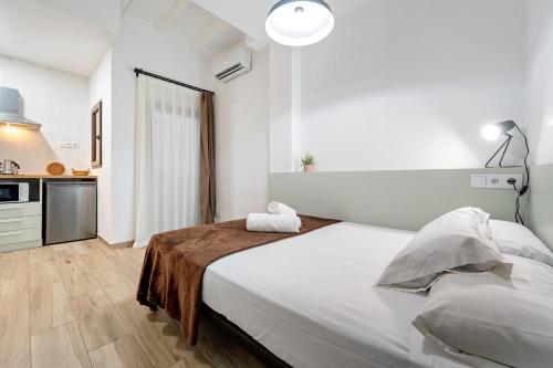 a white bedroom with a large bed and a kitchen at FORUM EXPERIENCE Adults Only in Tarragona