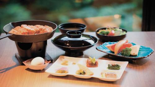 a table with plates of food and bowls of food at Aizu Higashiyama Onsen "Tsuki no Akari" self-service INN in Aizuwakamatsu