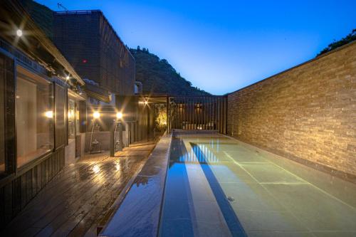a swimming pool on the side of a brick building at Aizu Higashiyama Onsen "Tsuki no Akari" self-service INN in Aizuwakamatsu