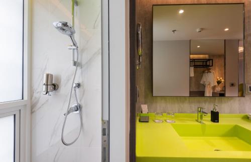 a bathroom with a yellow sink and a shower at Maitria Hotel Rama 9 Bangkok - A Chatrium Collection in Bangkok