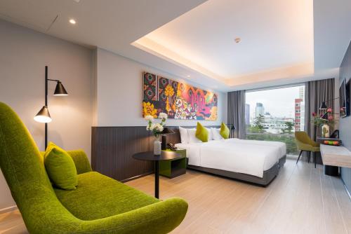 a bedroom with a white bed and a green chair at Maitria Hotel Rama 9 Bangkok - A Chatrium Collection in Bangkok