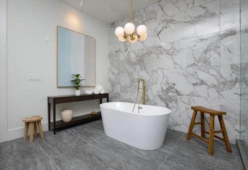 a bathroom with a white tub and a marble wall at Top Floor Penthouse Lofts in Atlanta
