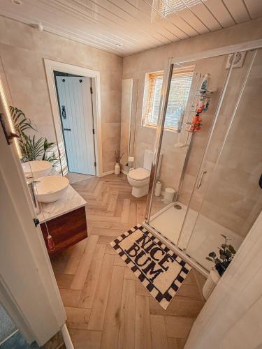 a bathroom with a shower and two sinks and a toilet at Smiley's Cottage in Doagh