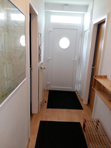 a hallway with a white door and a black rug at Haus Deichblick in Dornum