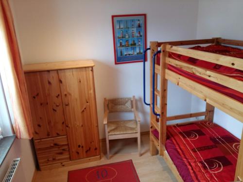a bedroom with a bunk bed and a chair at Haus Deichblick in Dornum