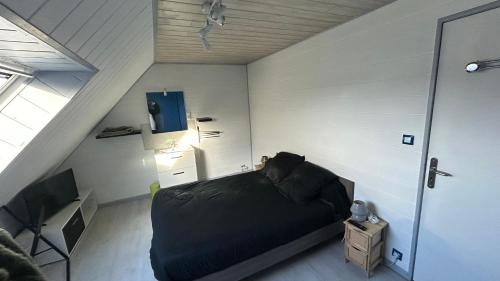 a bedroom with a black bed in a attic at Entre terre et mer in Combrit