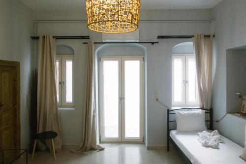 a bedroom with a bed and windows and a chandelier at Anna's House in Koufonisia