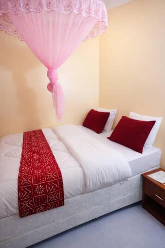 a bedroom with a large bed with red pillows at COLIBRI VILLA City Center in Gisenyi
